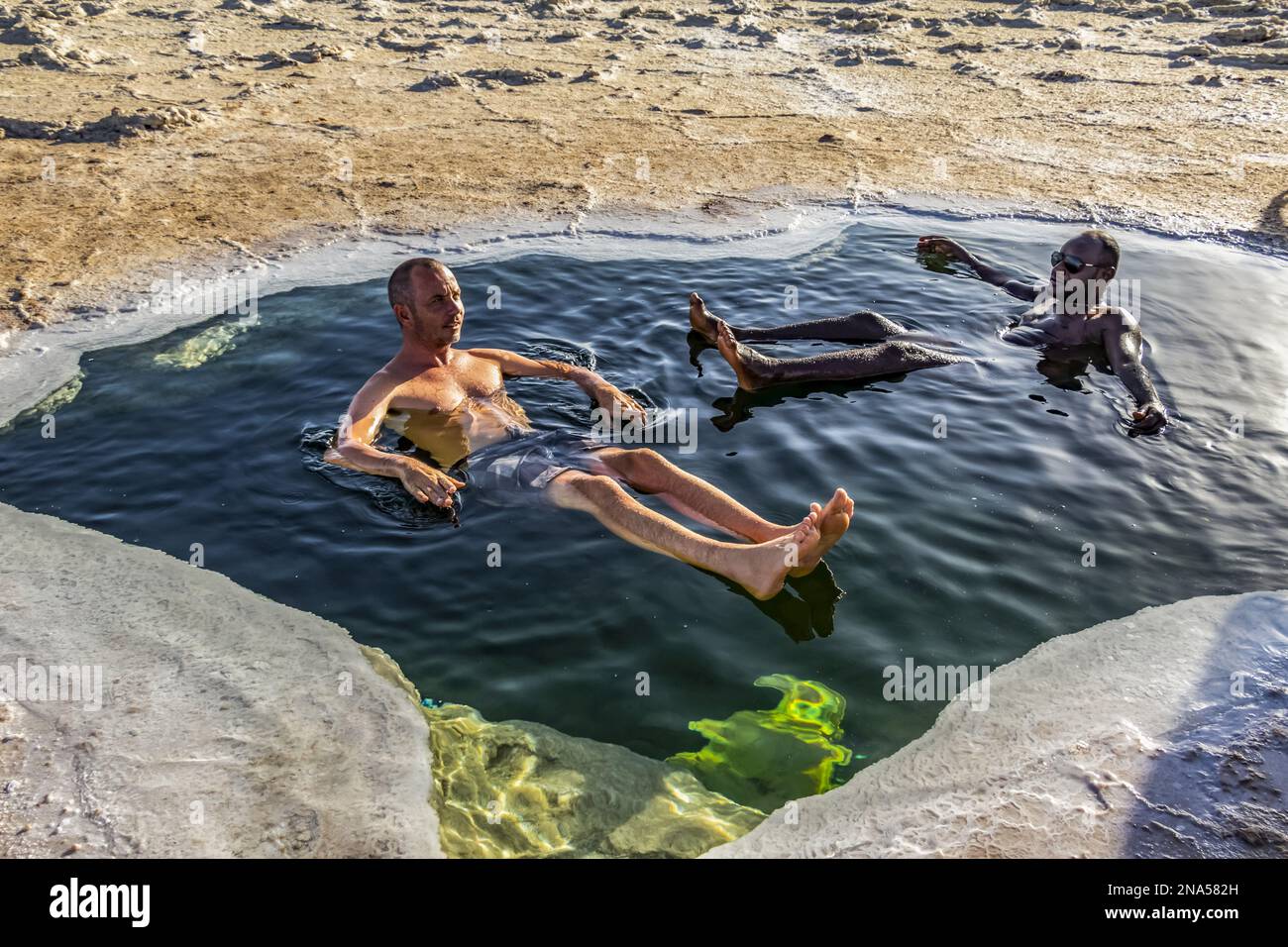 Hommes se baignant dans un bassin de saumure dans les salines du lac Karum (lac Assale), dépression de Danakil ; région d'Afar, Ethiopie Banque D'Images