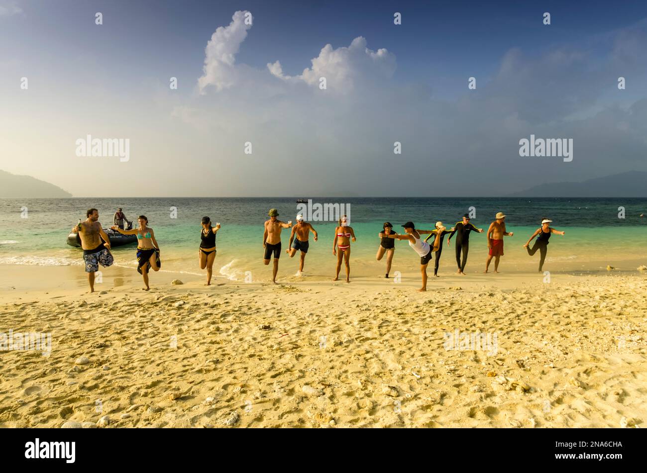 Passagers de croisière ayant une leçon d'aérobic sur une plage tropicale déserte en Papouasie-Nouvelle-Guinée ; Deka Deka Island, province de Milne Bay, Papouasie-Nouvelle-Guinée Banque D'Images