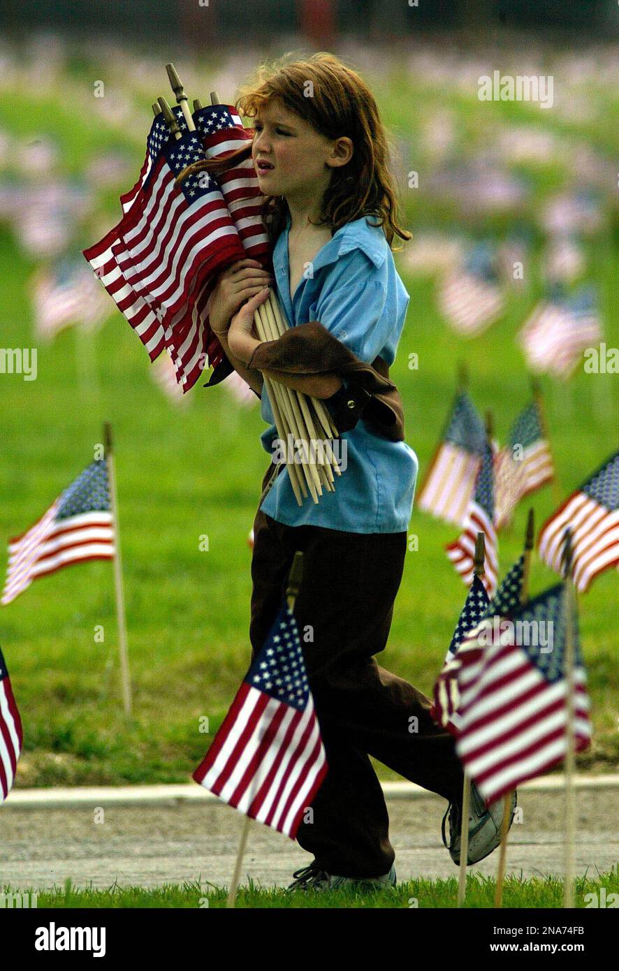 FILE - In this Saturday, May 29, 2004 file photo, Janine Key, 7, a Girl Scout from Woodland Hills, Calif., carries U.S. flags to plant at each grave in The Angeles National Cemetery for Memorial Day in Los Angeles. It's been 100 years since Juliette Gordon Low recruited the first scouts in Georgia. Low's original registration book from March of 1912 shows 102 recruits. Now there are 2.3 million active Girl Scouts nationwide. (AP Photo/Damian Dovarganes, File) Banque D'Images