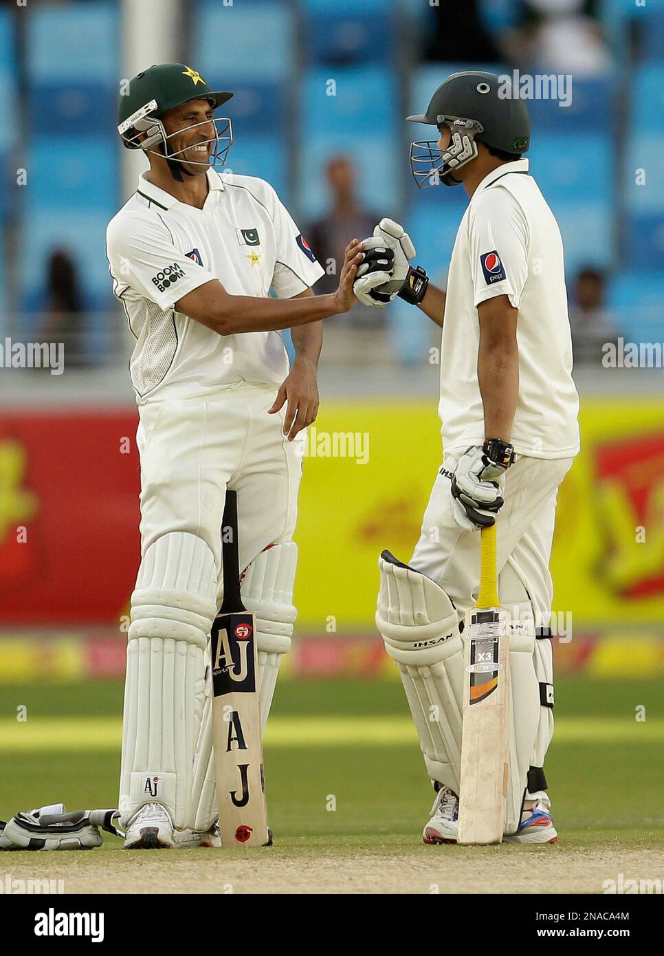 Pakistan's Younis Khan, left, is congratulated by his teammate Azhar Ali after scoring a century during the second day of the third cricket test match of a three match series between England and Pakistan at the Dubai International Cricket Stadium in Dubai, United Arab Emirates, Saturday, Feb. 4, 2012. (AP Photo/Hassan Ammar) Banque D'Images