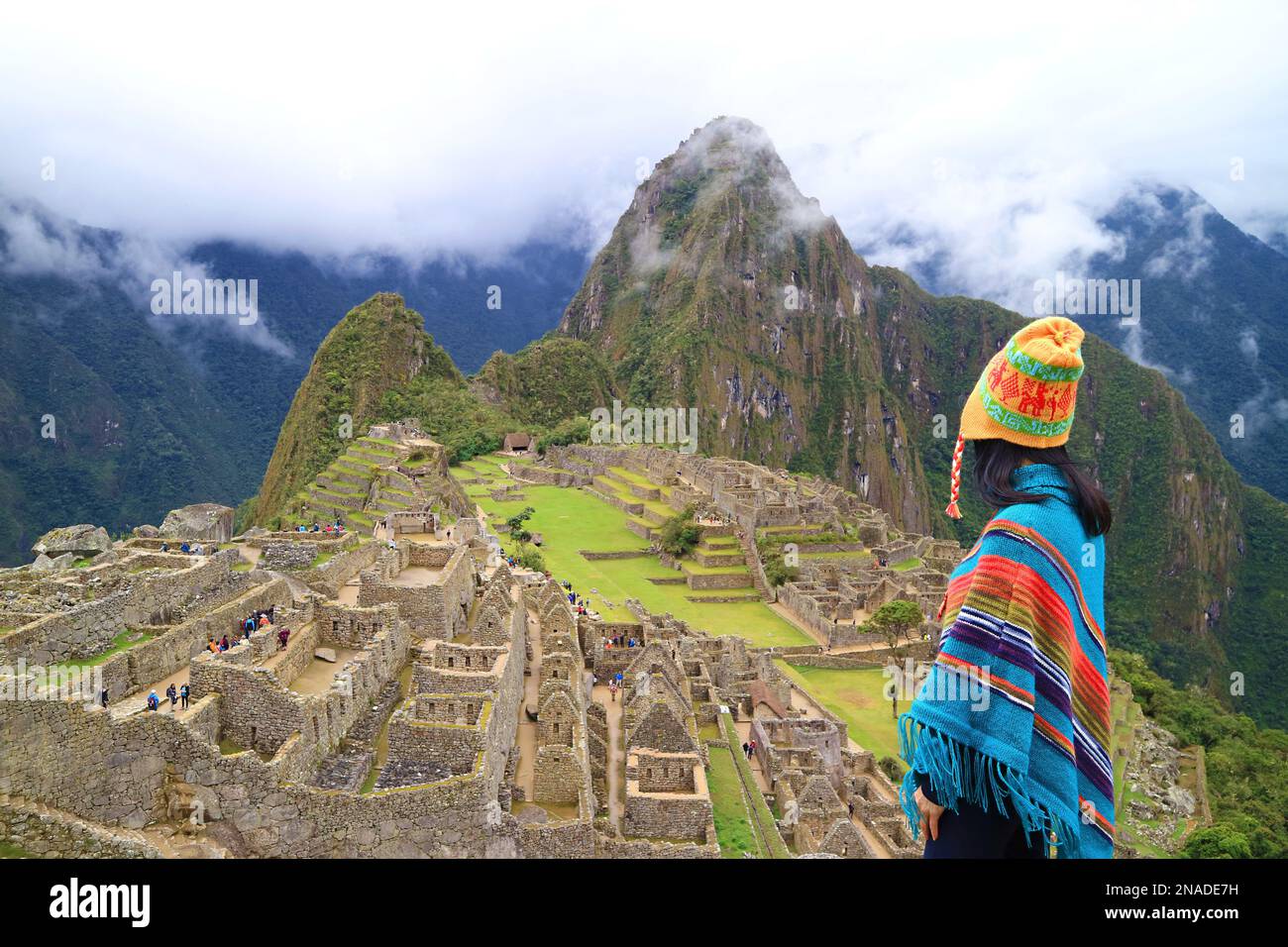 Femme à Poncho et au chapeau andin visitant l'étonnante Citadelle inca  antique de Machu Picchu, site classé au patrimoine mondial de l'UNESCO dans  la région de Cusco, Pérou, Amer du Sud Photo