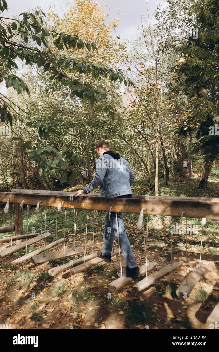 l'homme marche sur un pont suspendu en bois dans le parc Banque D'Images