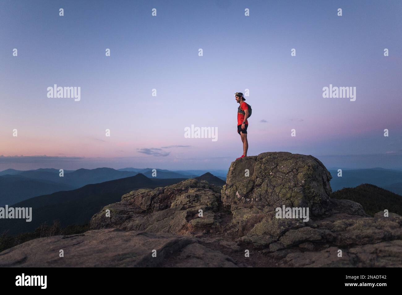 Coureur de sentier, homme debout sur le rocher au sommet de la montagne au lever du soleil Banque D'Images