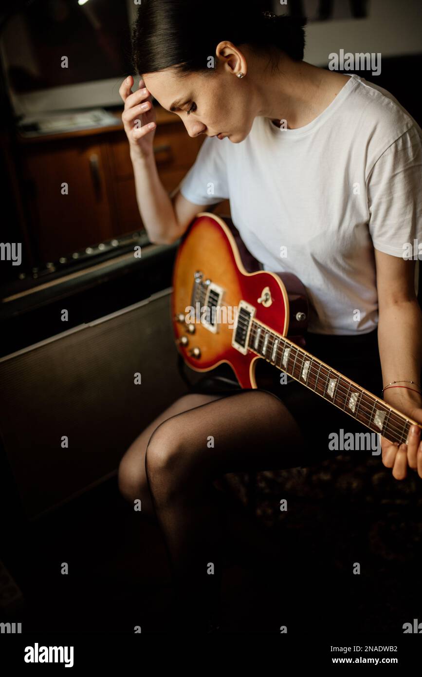 Fille solitaire avec une guitare électrique dans sa chambre Banque D'Images