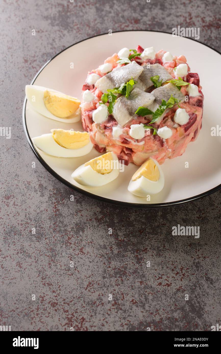 Salade de hareng ou plat traditionnel Sillsallad de cuisine scandinave en gros plan dans une assiette sur la table. verticale Banque D'Images