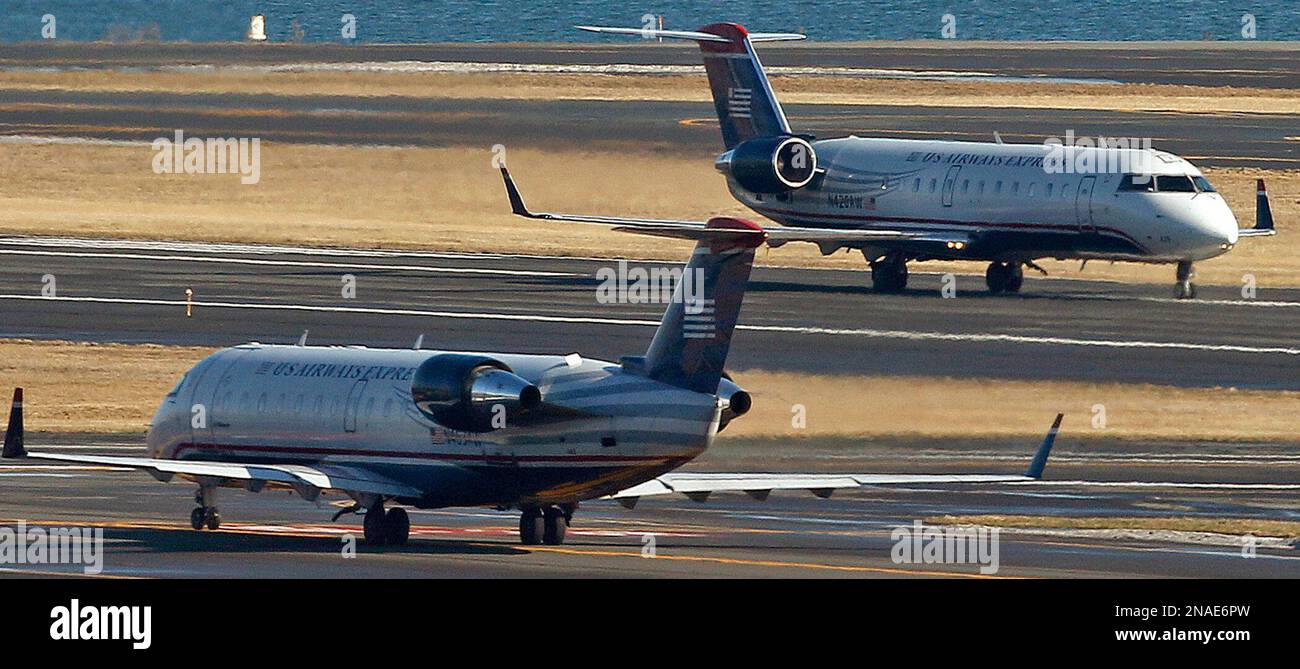 A US Airways jet, rear, passes a taxiing jet on a take-off roll at Logan Airport in Boston Tuesday, Jan. 24, 2012. US Airways Group Inc. said Wednesday its net income fell 35 percent in the last three months of 2011 as rising passenger revenue wasn’t enough to offset a steep increase in fuel prices. (AP Photo/Charles Krupa) Banque D'Images