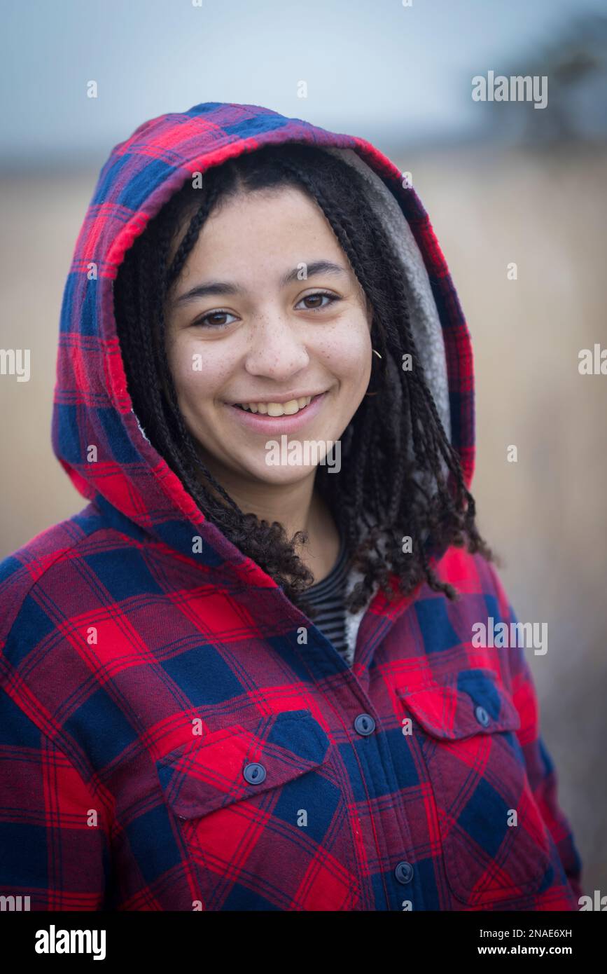 portrait de la jeune femme biraciale souriant avec des tresses et une cagoule Banque D'Images