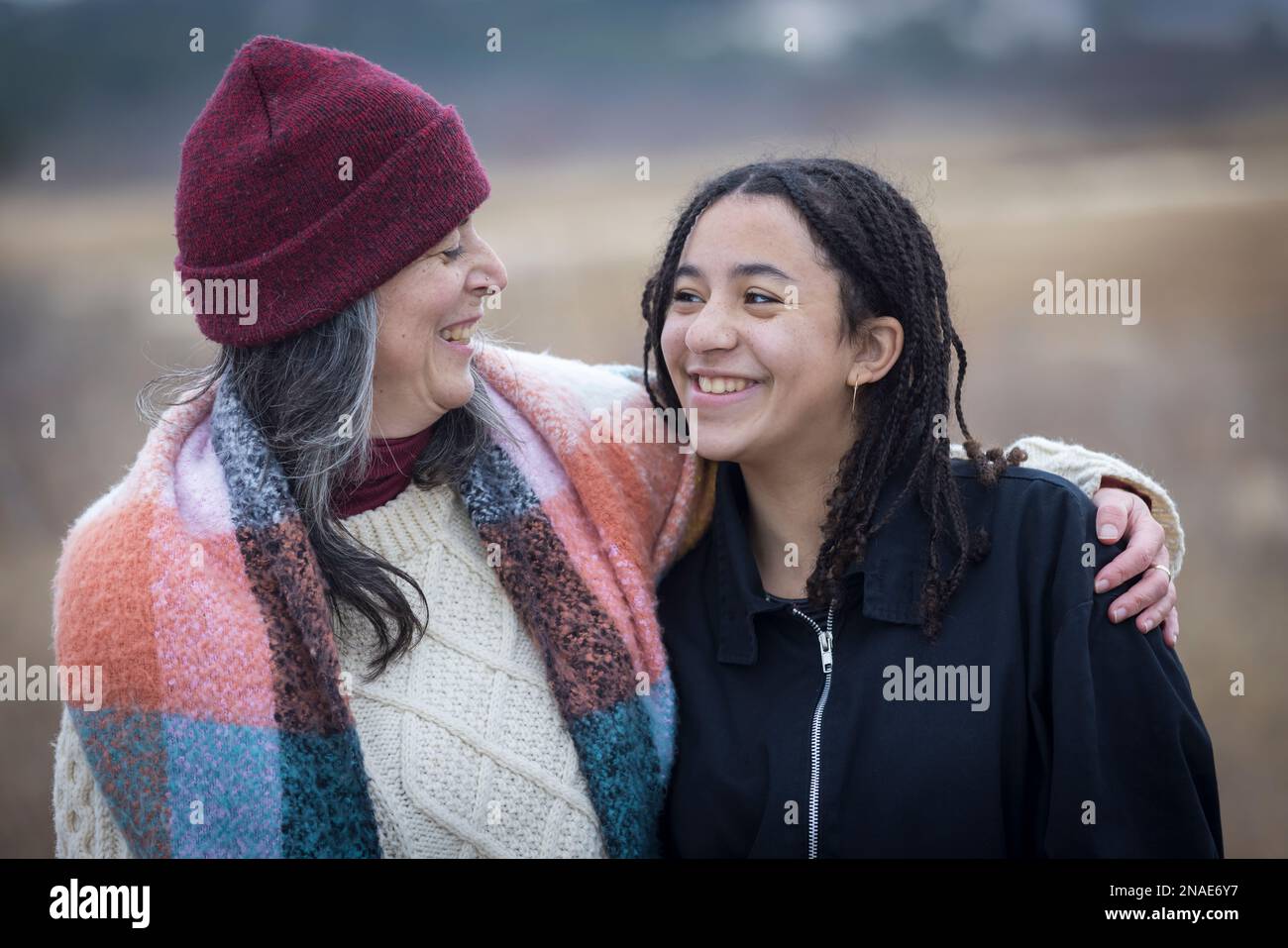 mère blanche et fille de l'adolescence biracial souriant l'une à l'autre Banque D'Images