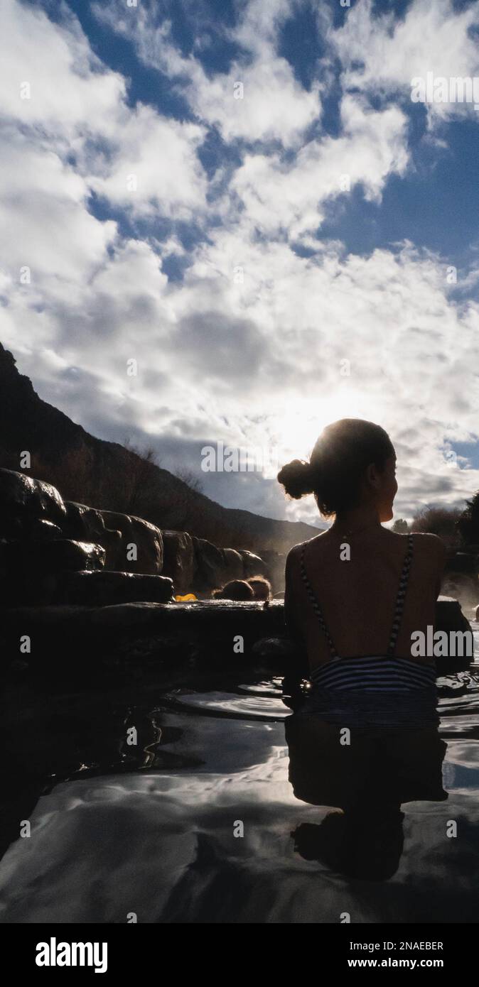 femme dans les sources chaudes naturelles au coucher du soleil avec la vapeur et le contre-jour Banque D'Images