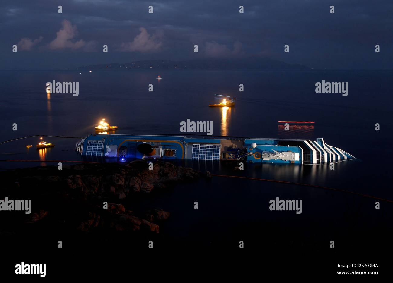 The grounded cruise ship Costa Concordia lies on its side off the Tuscan island of Giglio, Italy, Monday, Jan. 23, 2012. Italian officials say Monday two more bodies have been pulled from the wreckage of a cruise liner capsized off the Tuscan coast, bringing the number of confirmed dead to 15. The national civil protection agency official in charge of the search said Monday that divers recovered the bodies of two women from the ship's internet cafe. (AP Photo/Pier Paolo Cito) Banque D'Images