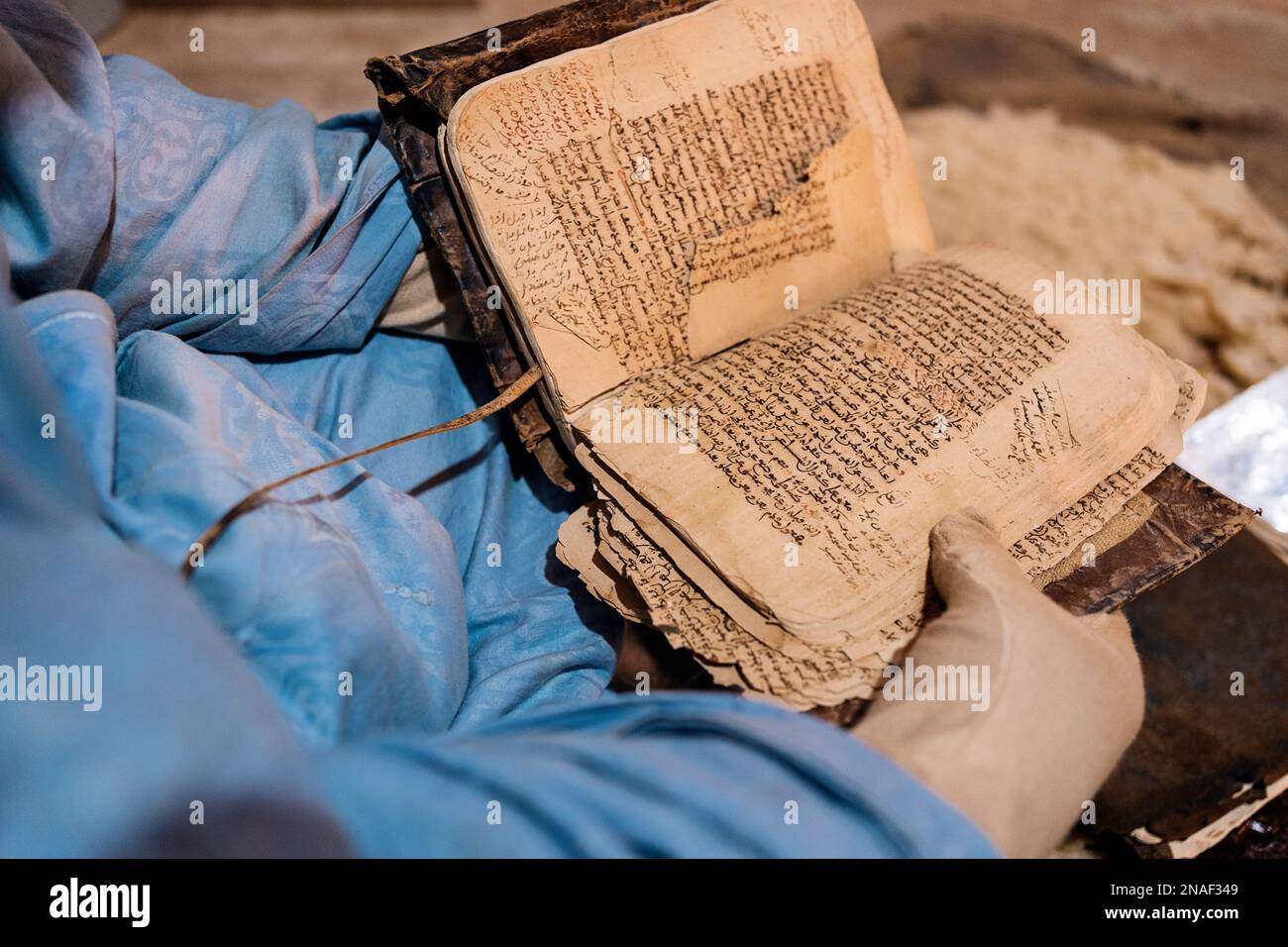 Livres anciens Qur'anic présentés par le bibliothécaire portant des gants Banque D'Images