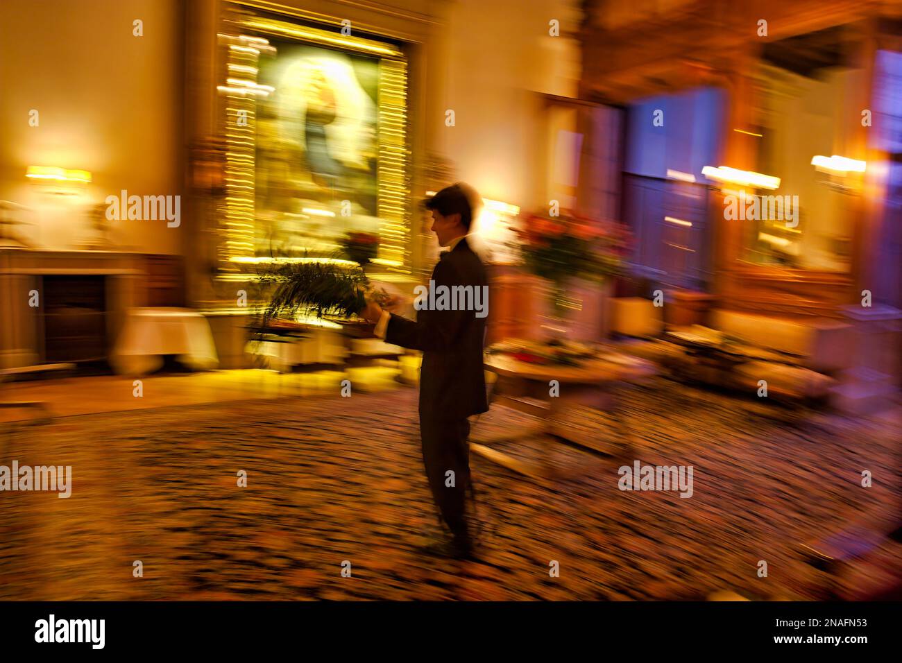 Le serveur prépare une salle à manger en rafraîchissant les arrangements floraux dans un hôtel somptueux dans les Alpes suisses ; préparé Moritz, Suisse Banque D'Images