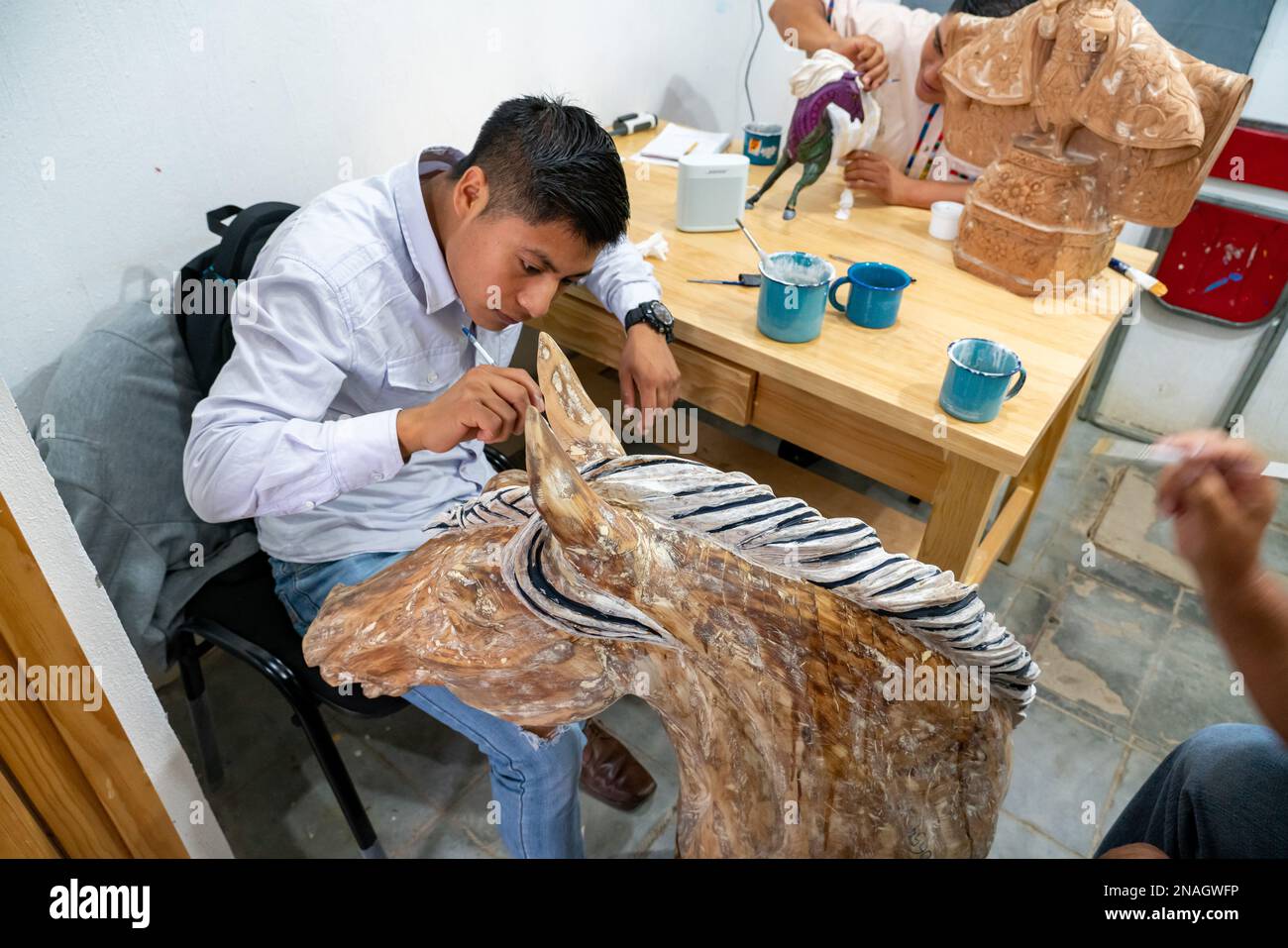 Un artisan commence à peindre un animal spirituel d'alebrije dans un atelier à San Martin Tilcajete, Oaxaca, Mexique. Banque D'Images