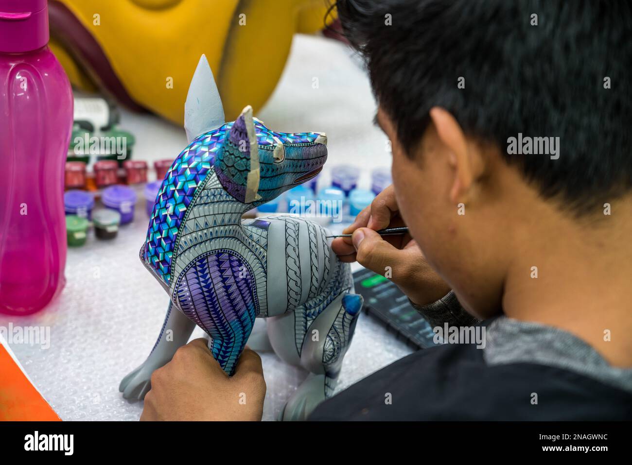 Un artisan complexe peint Zapotec dessins sur un animal esprit alebrije dans un atelier à San Martin Tilcajete, Oaxaca, Mexique. Banque D'Images