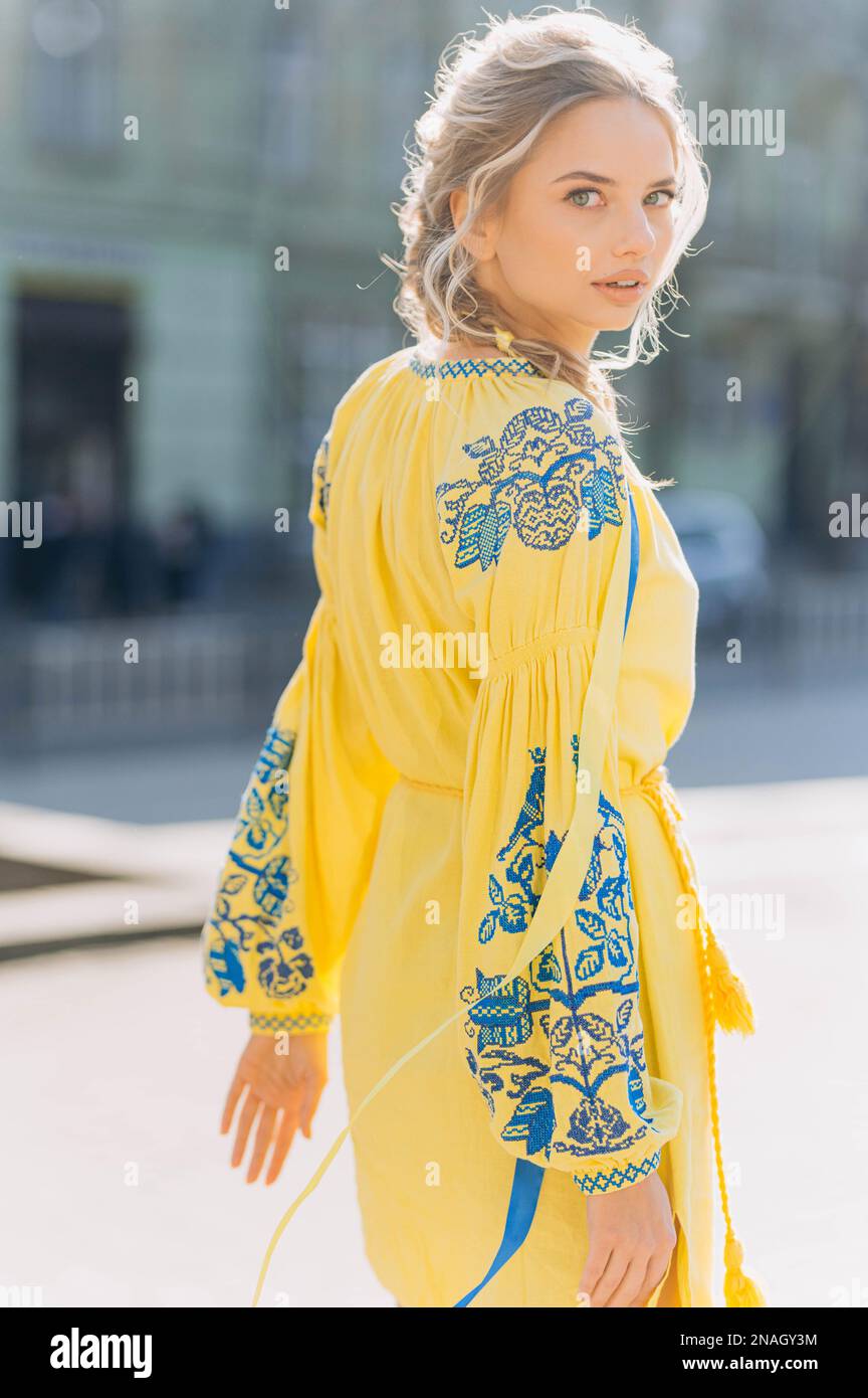 jeune fille dans une robe jaune moderne traditionnelle dans la rue. Femme ukrainienne dans une robe brodée Banque D'Images