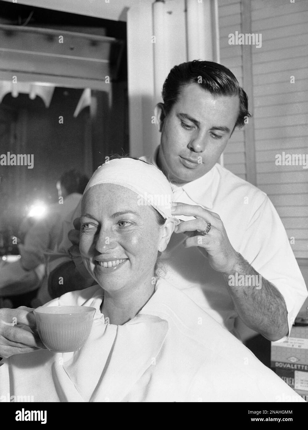 With a mask and make up, young and attractive Agnes Moorehead is fashioned into a 105-year-old woman. To prepare her for the role of the centenarian Juliana in “The Last Moment,” make-up artist Buddy Westmore first obtained a Negacol impression of her face. The job took a week. From this he made a mold, into which was poured plastic material and baked for three hours. Nine masks were made in this manner, but only three were acceptable. Each morning, before facing the cameras, the actress sits for four hours while the mask and make-up are applied. In addition to the changes to her face, her arm Banque D'Images