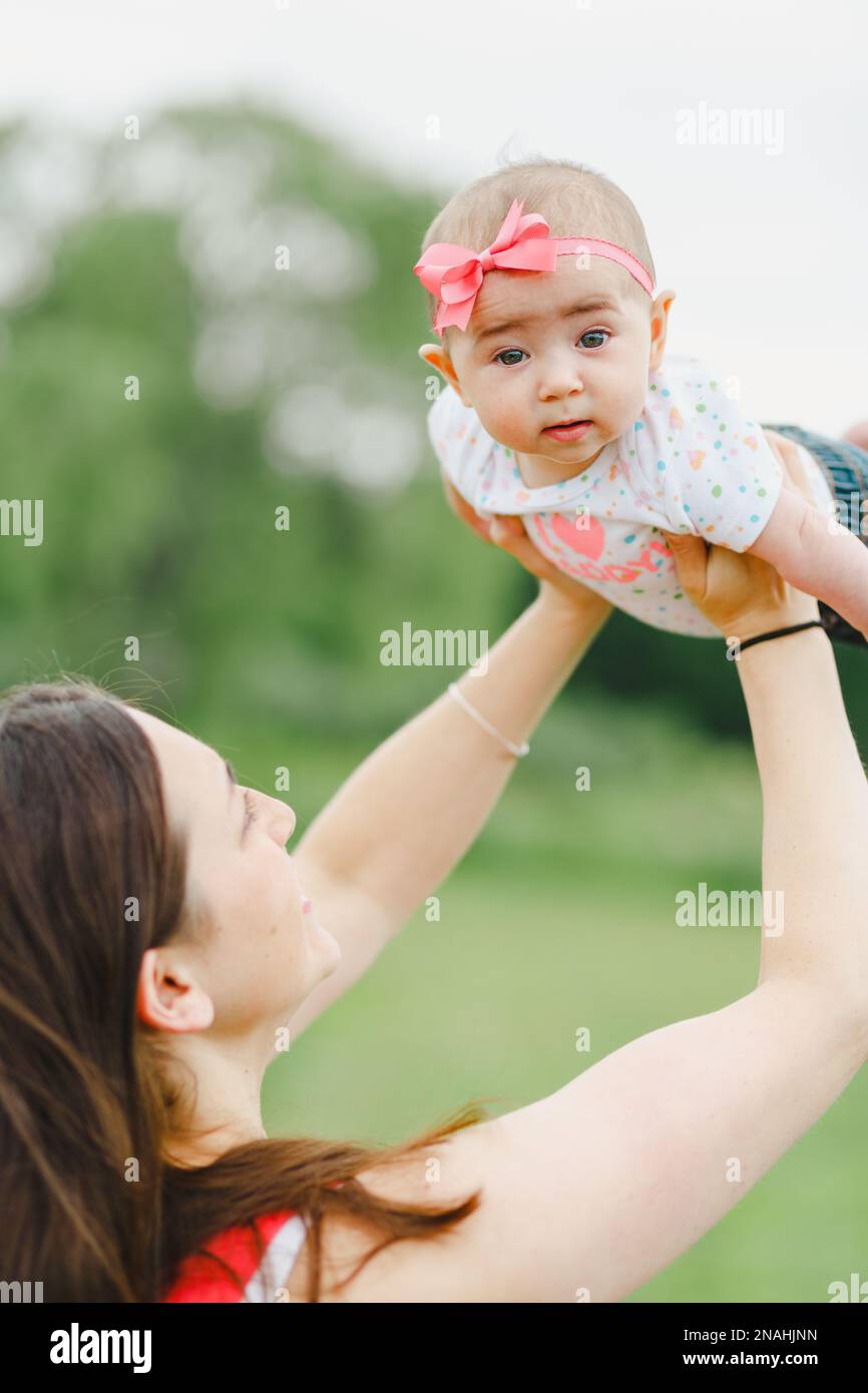 Jeune femme adulte regardant et tenant bébé fille avec enfant regardant l'appareil photo Banque D'Images