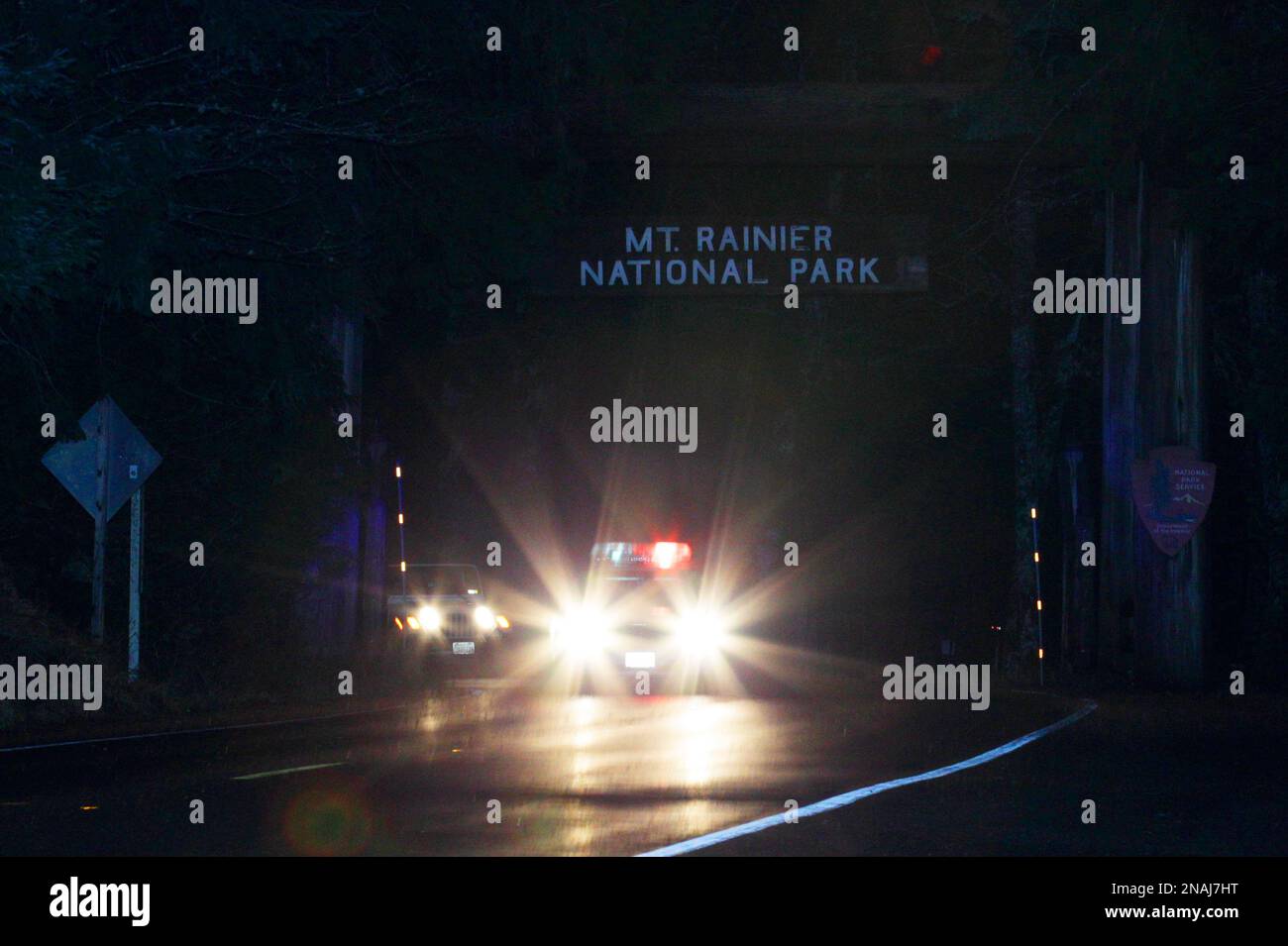 A law-enforcement vehicle leads a convoy of evacuees out of Mount Rainier National Park in the early morning hours of Monday, Jan. 2, 2012 in Washington state. More than 100 people were kept in guarded conditions at a visitors center in the park until the evacuation as a safety precaution after a gunman shot and killed a park ranger during a traffic stop, fled on foot, and remained at-large overnight. (AP Photo/Ted S. Warren) Banque D'Images