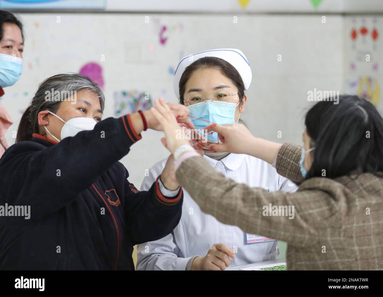 HUAI'AN, CHINE - le 13 FÉVRIER 2023 - Une infirmière dirige un malade mental pour jouer à un jeu appelé « corde de fleur » dans Huai 'an, province de Jiangsu, Chine, Fe Banque D'Images