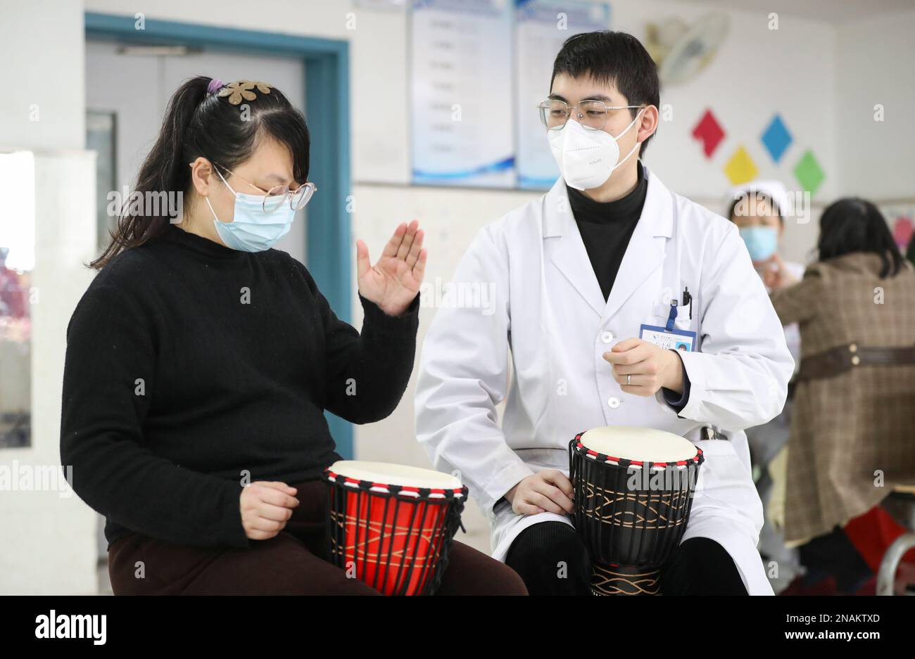 HUAI'AN, CHINE - 13 FÉVRIER 2023 - Un physiothérapeute de musique enseigne à un malade mental de jouer un tambour africain à Huai 'an, province de Jiangsu, Chi Banque D'Images