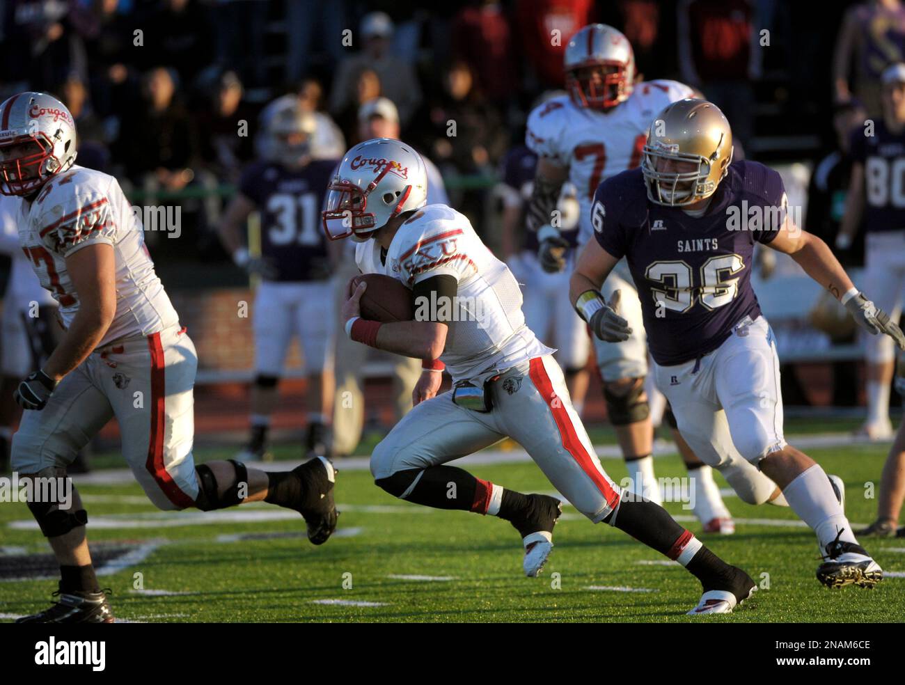 Saint Xavier quarterback Jimmy Coy, center, runs for a touchdown as Carroll College defensive end Dakota Amy (36) gives chase during the first half of the NAIA national championship college football game on Saturday, Dec.17, 2011, in Rome, Ga. (AP Photo/John Amis) Banque D'Images
