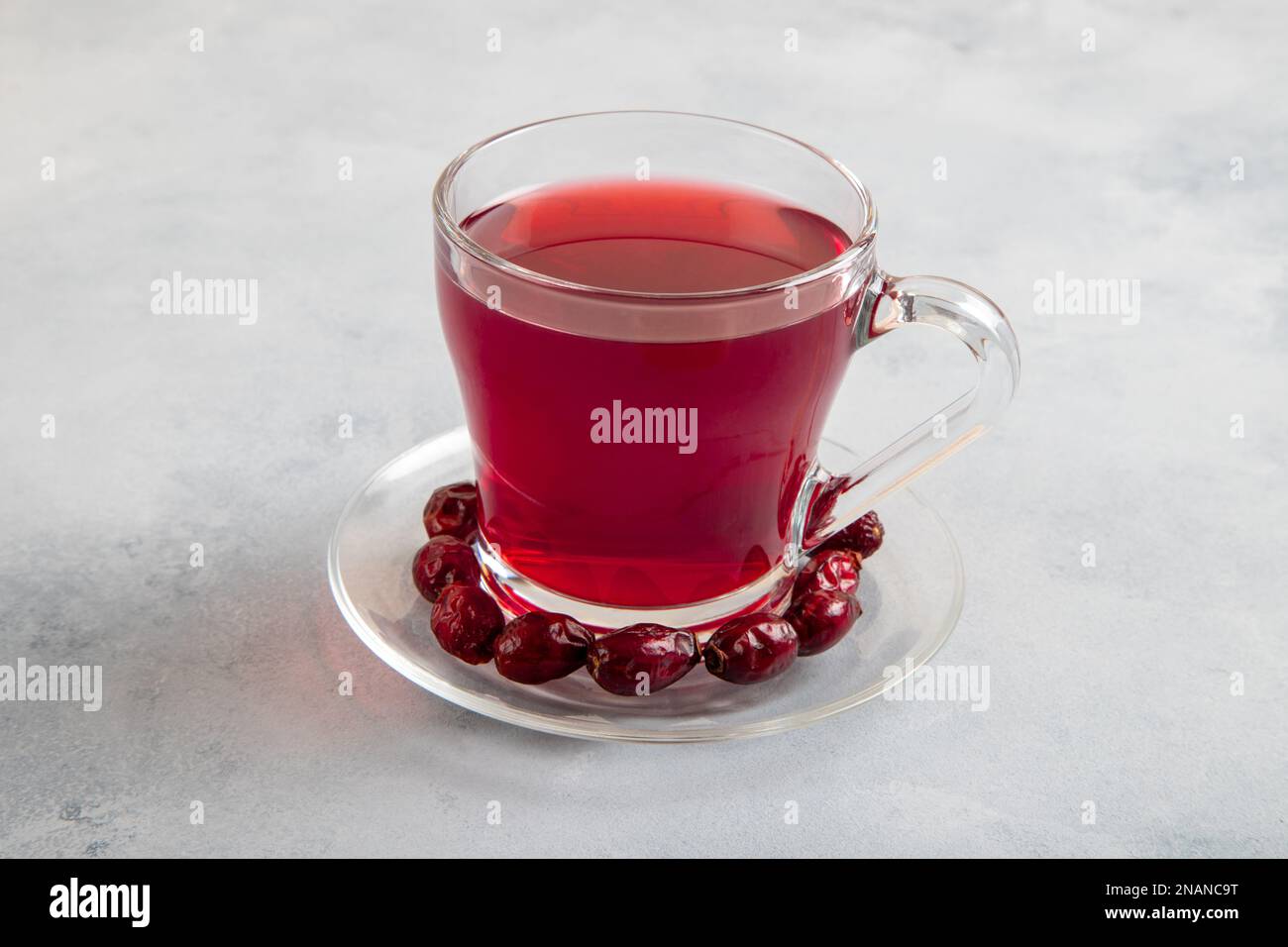 Un verre de thé aux hanches roses et de graines de rosehip sur fond bleu vif Banque D'Images