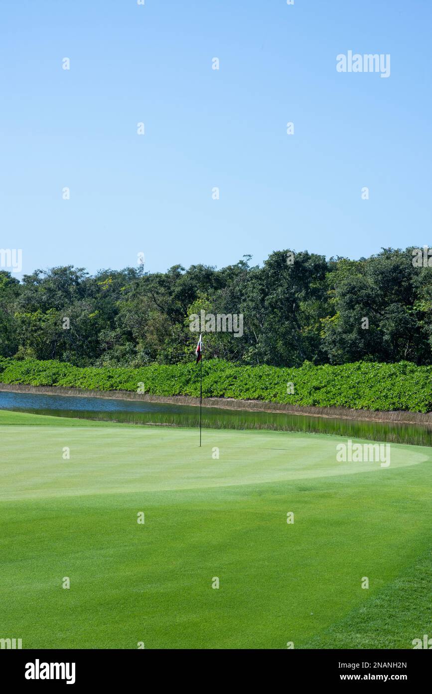 Gros plan du vert avec drapeau et obstacles d'eau d'un club de golf au Mexique Banque D'Images