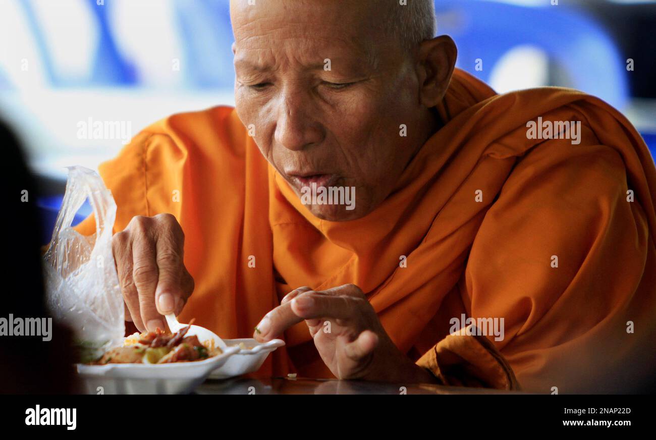 Former Khmer Rouge cadre member and Buddhist monk Tep He, 63, takes his breakfast outside the court hall before the second day of trial of the U.N.-backed war crimes tribunal in Phnom Penh, Cambodia, Tuesday, Dec. 6, 2011. Three senior leaders of Cambodia's brutal Khmer Rouge regime on Tuesday are continuing questioned at a U.N.-backed tribunal over their roles in the deaths of an estimated 1.7 million people when their movement held power in the 1970s. (AP Photo/Heng Sinith) Banque D'Images