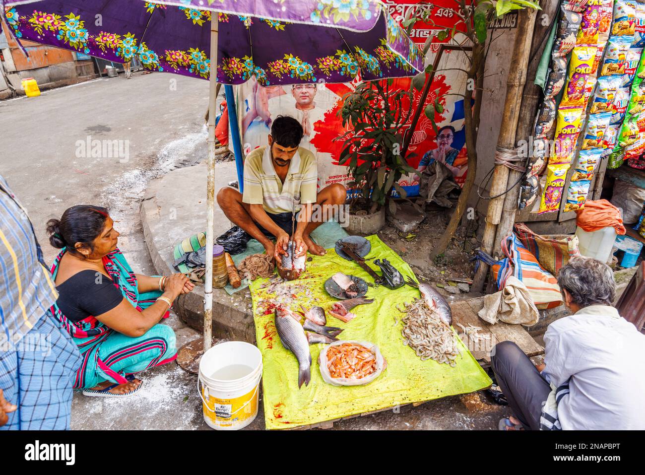 Détenteur local de la rue coupant, trancher et préparer le poisson à vendre dans un stalle situé sur le bord de la route à Fariapukur, Shyam Bazar, Kolkata, Bengale occidental, Inde Banque D'Images