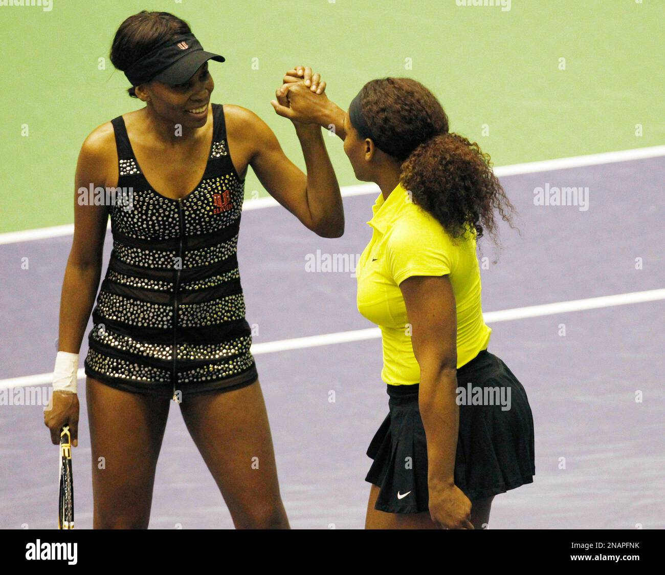 Venus Williams, left, and her sister Serena, of the United States, celebrate after winning a point during an exhibition doubles tennis match against Italy's Flavia Pennetta and Francesca Schiavone, in Milan, Italy, Saturday, Dec. 3, 2011. (AP Photo/Antonio Calanni) Banque D'Images