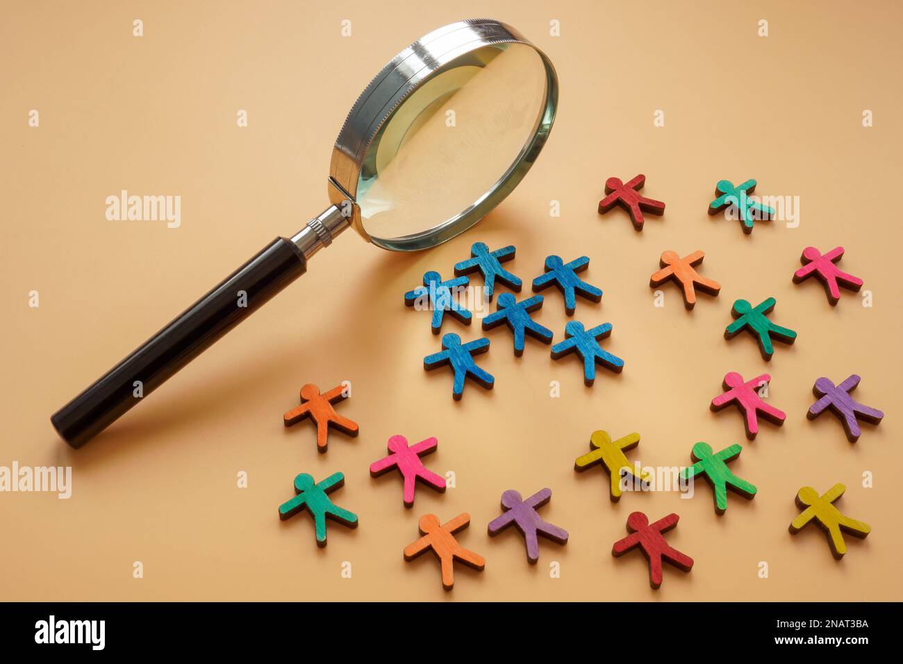 Loupe et petites figurines colorées. Concept d'analyse de segmentation. Banque D'Images