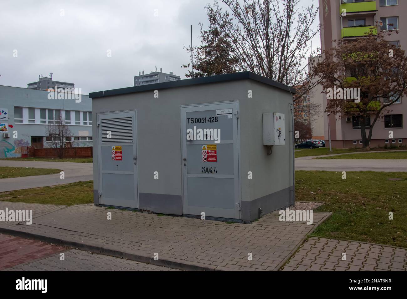 Bâtiment de salle de transformateur électrique avec portes grises et panneaux de danger jaunes contre le ciel bleu dans la ville de Nitra en Slovaquie Banque D'Images