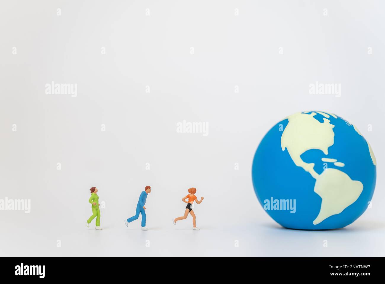 Concept mondial de santé sportive. Groupe de coureurs miniature figure personnes courir à mini World ball sur fond blanc avec espace de copie. Banque D'Images