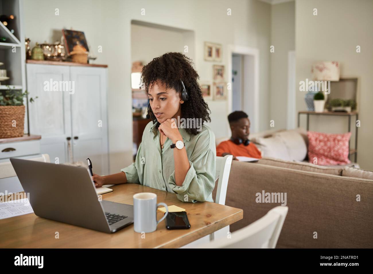 Une jeune femme africaine en communication tout en travaillant à distance de chez elle Banque D'Images