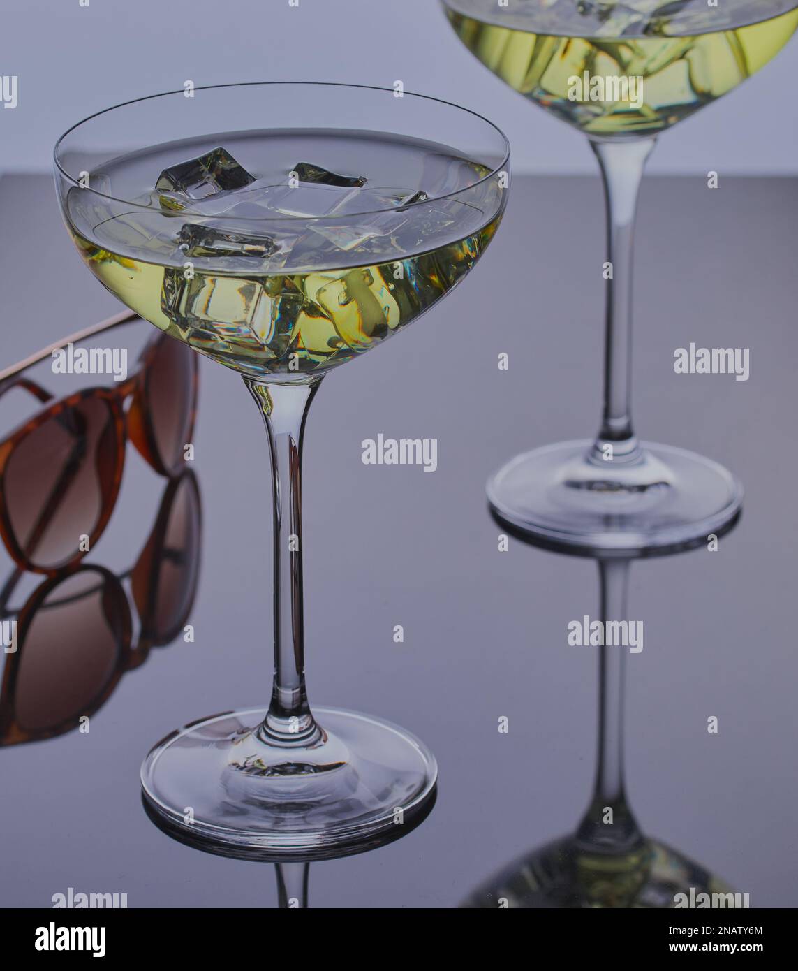 Deux cocktails avec glace sur une surface réfléchissante avec une paire de lunettes de soleil. Banque D'Images