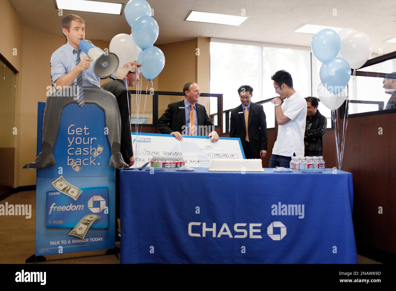 Simon Griffiths, left, market manager for Chase Cal Central Market, presents a $1 million check to Chase Freedom "Get Your Cash Back" $1 Million Dollar Facebook Sweepstakes Winner Steven Haryono, 22, second right, of Fremont at the Fremont Blvd. Chase Bank branch in Fremont, Calif., Wednesday, Nov. 16, 2011. (Alison Yin/AP Images for Chase Bank) Banque D'Images