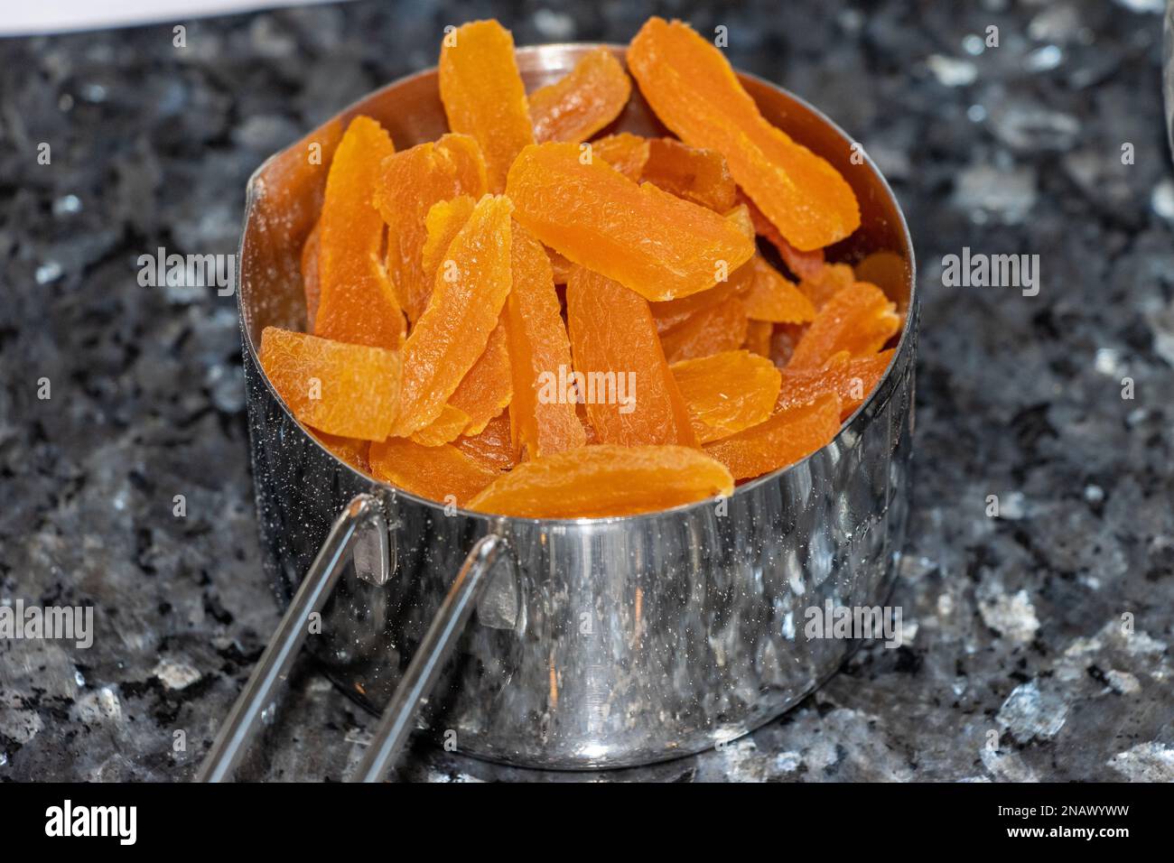 abricots séchés dans une tasse de métal sur une surface de granit. Banque D'Images