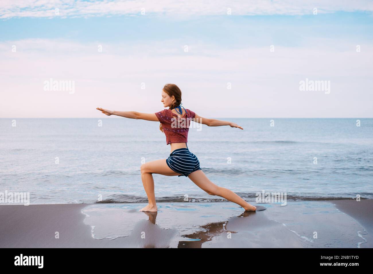 Active Sport redhead femme faisant du yoga sur la plage au Monténégro vue latérale, Femme est dans les vêtements de sport à la plage de la mer Adriatique Banque D'Images