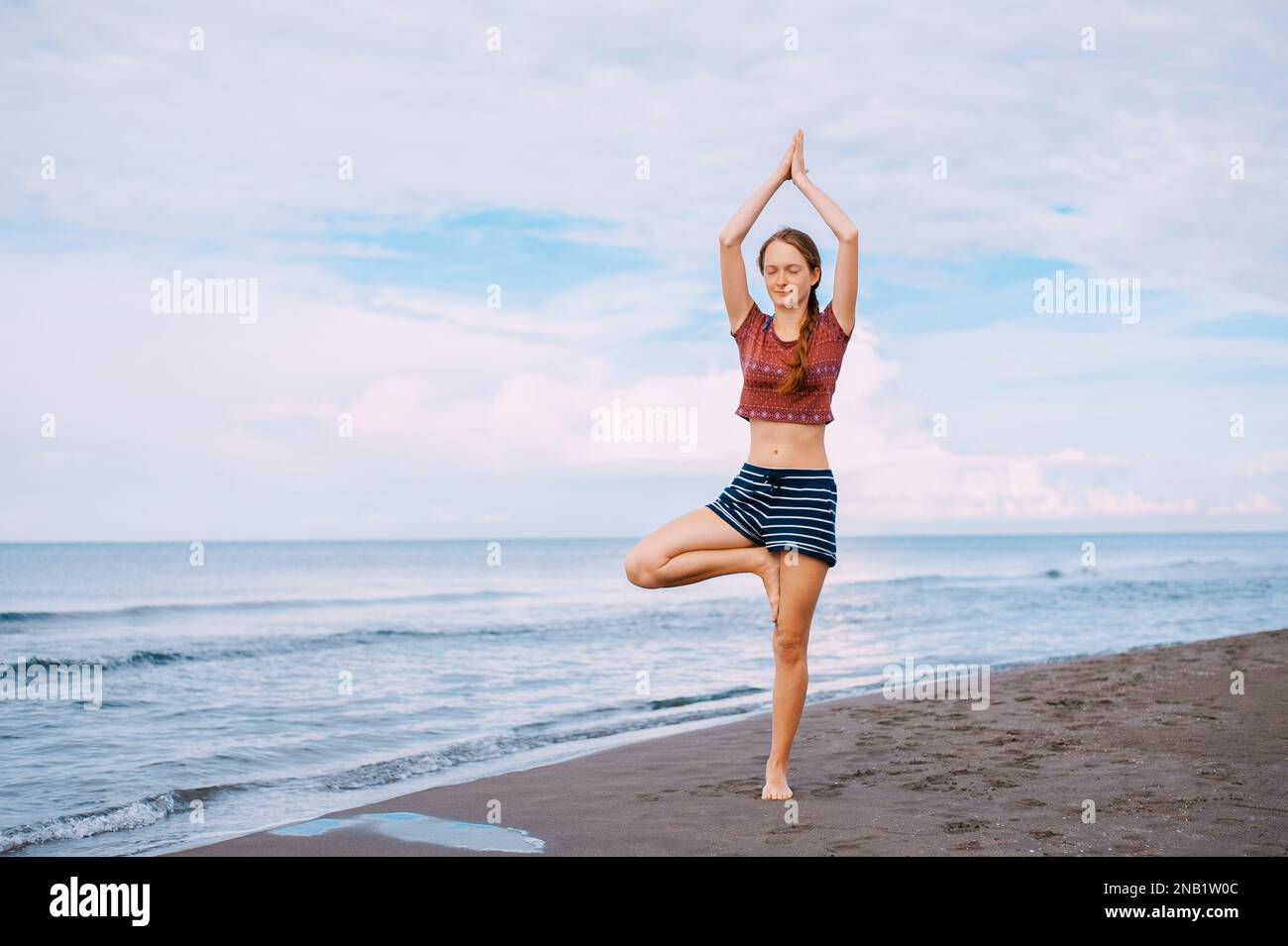 Active Sport redhead femme faisant du yoga sur la plage au Monténégro vue latérale, Femme est dans les vêtements de sport à la plage de la mer Adriatique Banque D'Images