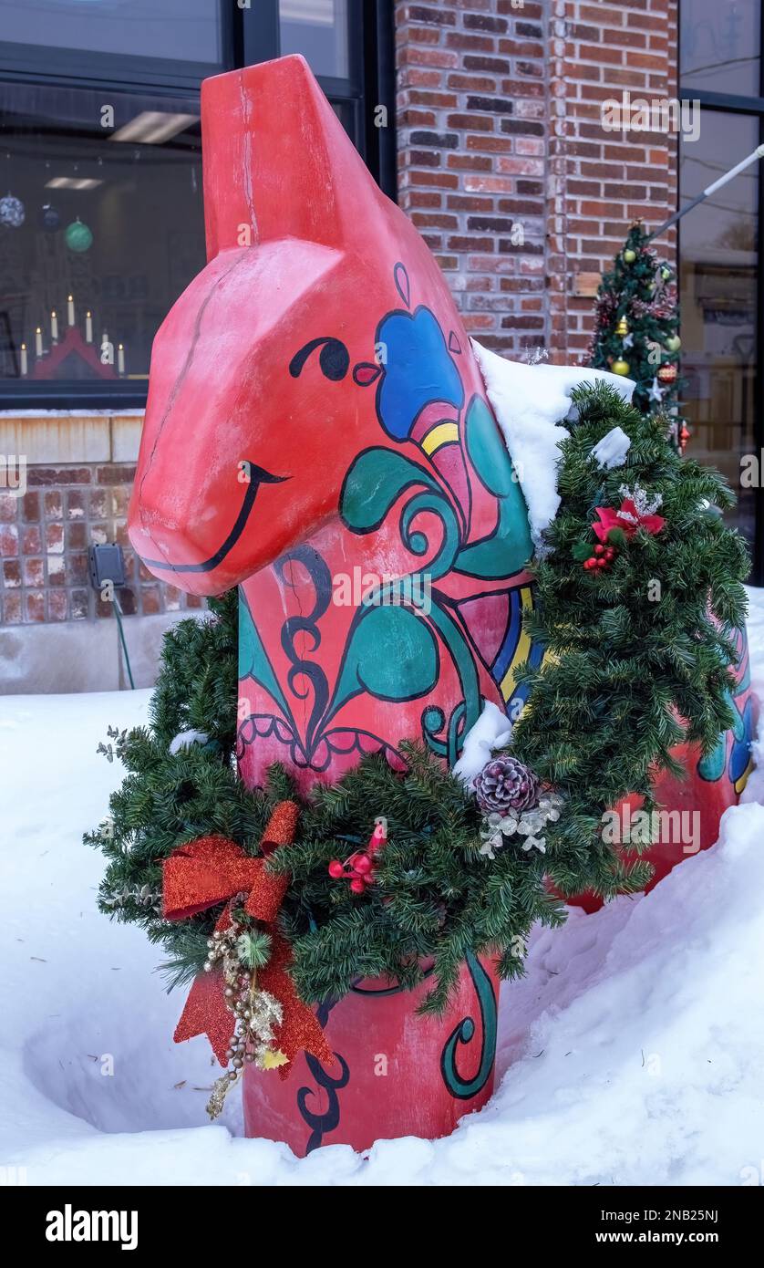 Un cheval de dala suédois rouge coloré avec une belle couronne de Noël autour de lui lors d'une journée d'hiver à Scandia, Minnesota États-Unis. Banque D'Images
