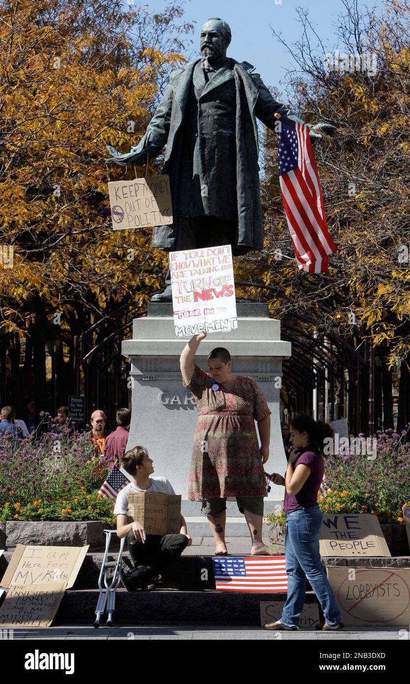 Protesters stand beneath a statue of President James Garfield, Monday, Oct. 10, 2011, in Cincinnati's Piatt Park. Hundreds of protesters marched in the city over the weekend and a small group continues to camp out downtown. (AP Photo/Al Behrman) Banque D'Images