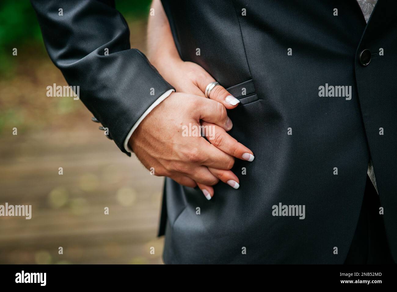 Un gros plan de la mariée tenant fermement la main de la mariée et gardant dans son costume Banque D'Images