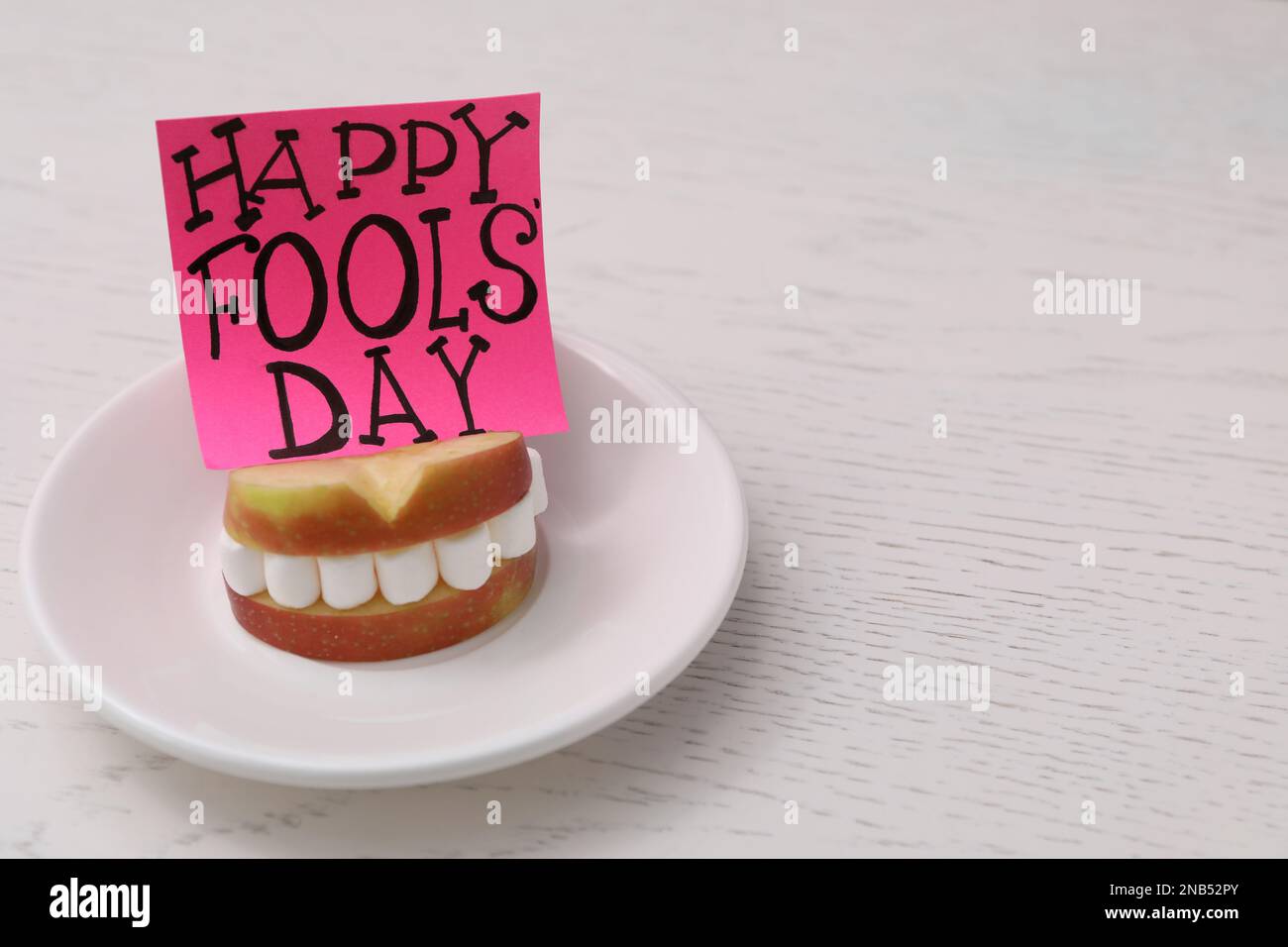 Mots Happy Fool's Day et sandwich de tranches de pomme avec guimauves sur une table en bois. Espace pour le texte Banque D'Images