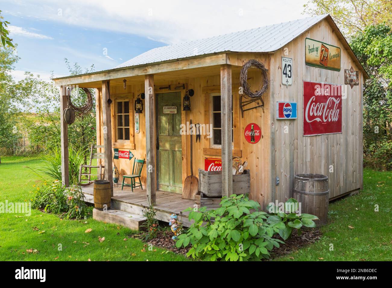 Ancien hangar de rangement en bois de pin de style rustique avec toit en tôle ondulée et décoré de Coca-Cola vintage et de 7up panneaux pour boissons. Banque D'Images