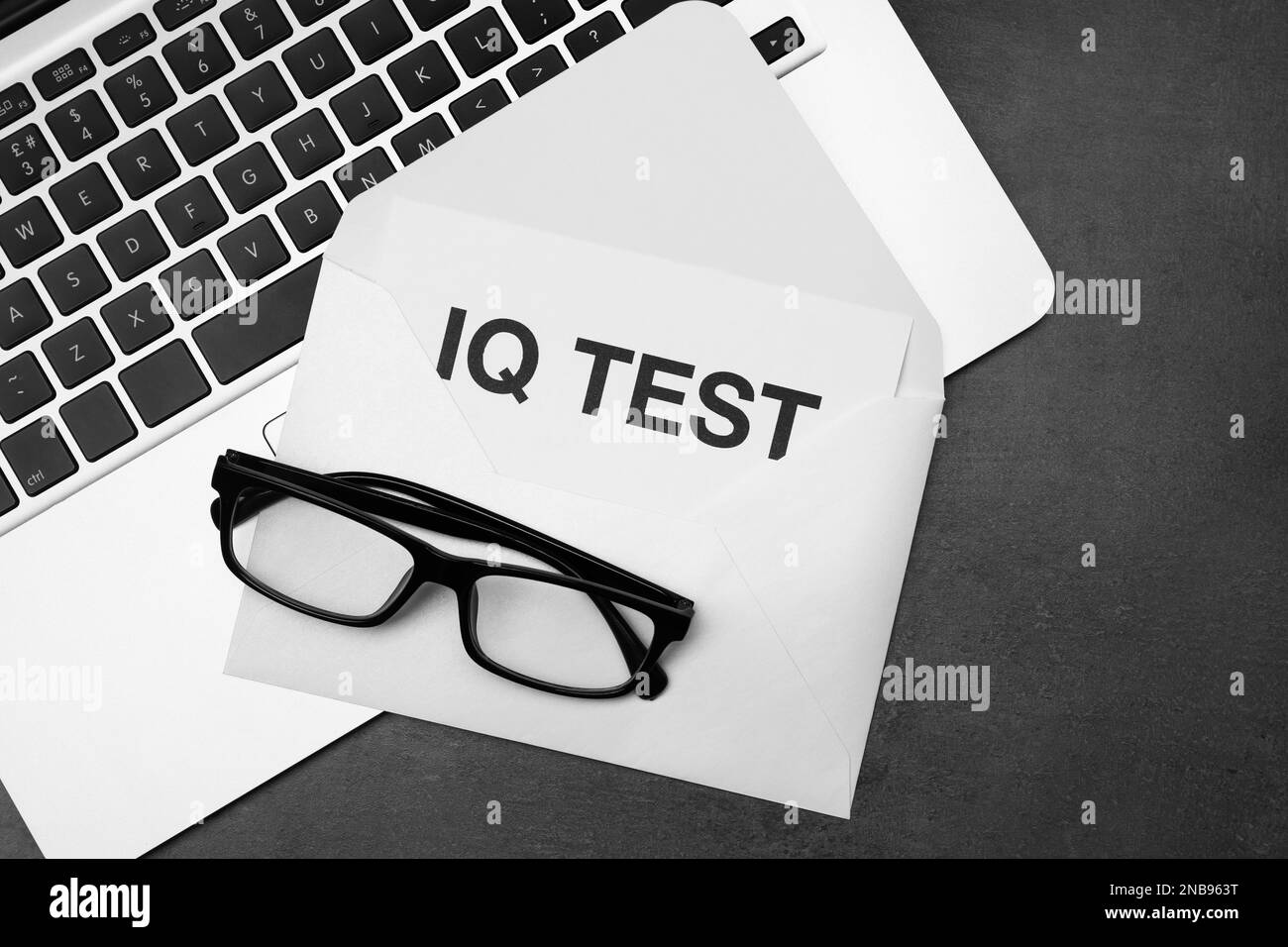 Papier avec mots IQ Test dans une enveloppe, des lunettes et un ordinateur portable sur une table noire, à plat Banque D'Images Papier avec mots IQ Test dans une enveloppe, des lunettes et un ordinateur portable sur une table noire, à plat Banque D'Images