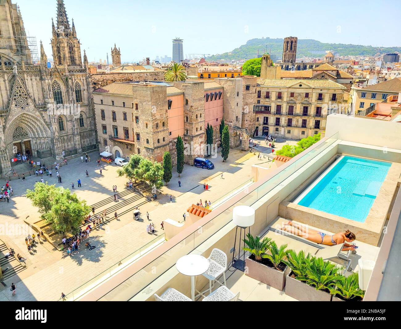 Une jeune femme baignera de soleil près d'une piscine dans un hôtel de luxe sur le toit surplombant la cathédrale de Barcelone, en Espagne. Banque D'Images