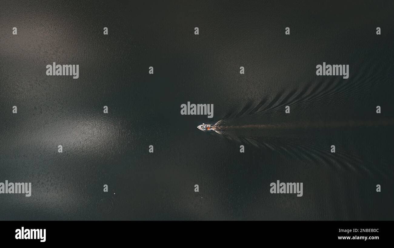 Vue sur un bateau traversant l'eau sombre du lac. Banque D'Images