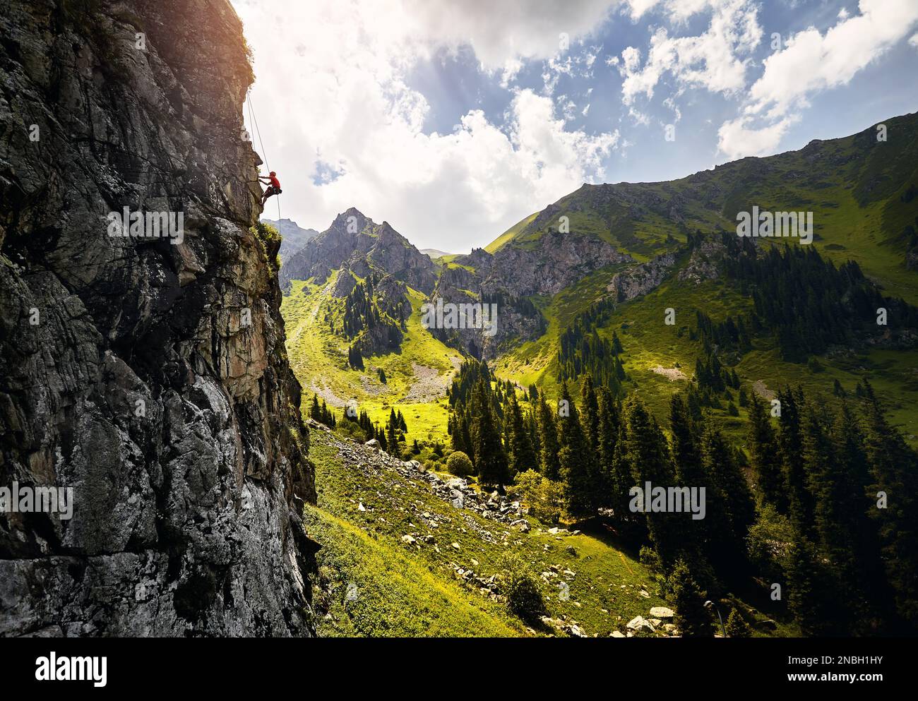 Faites monter un athlète en forme d'homme fort dans la roche de silhouette grimpant sur le mur vertical haut aux montagnes Tyan Shan au Kazakhstan Banque D'Images