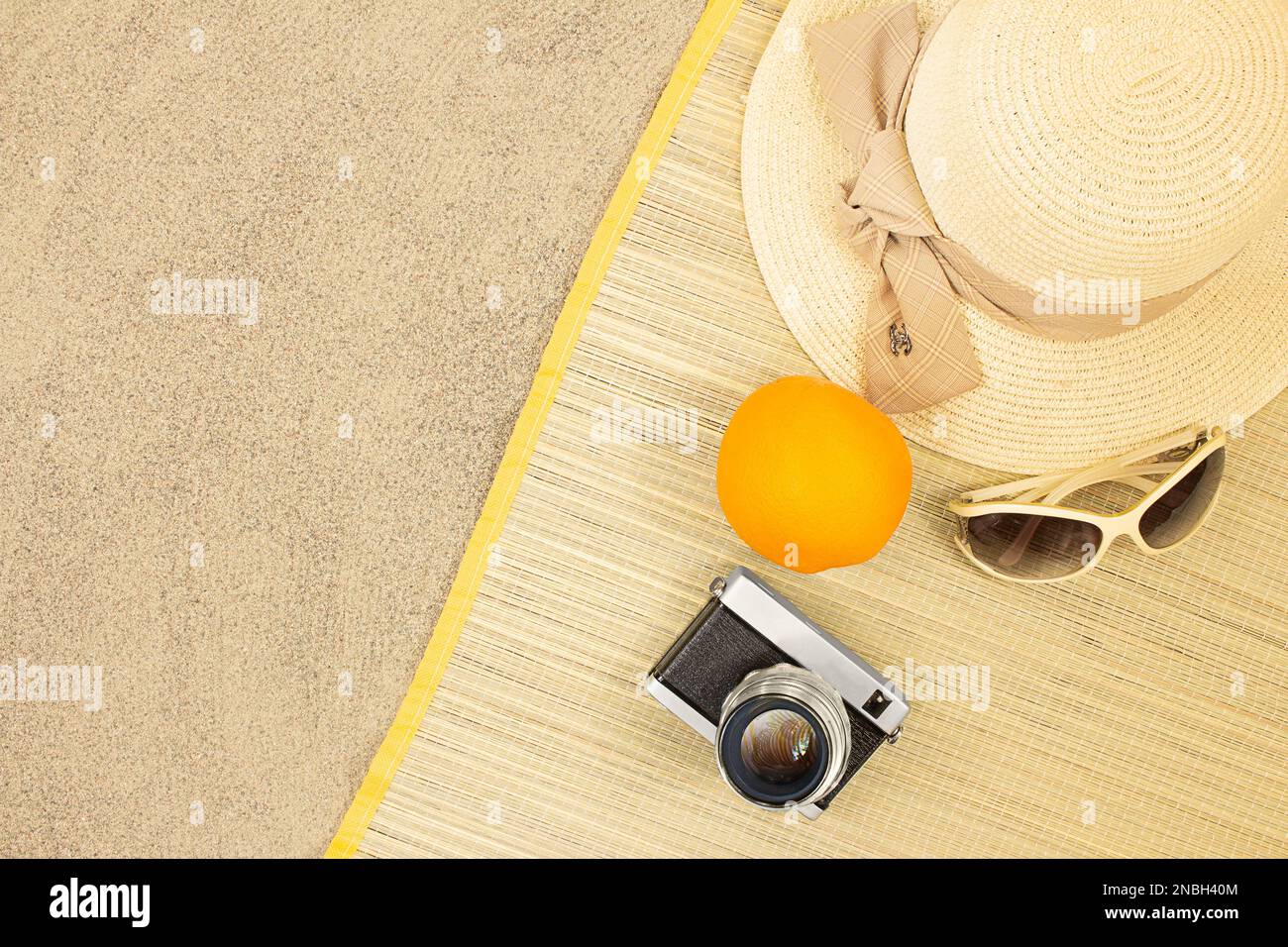 Chapeau de paille à l'orange, lunettes de soleil, appareil photo sur un solarium sur sable de plage. Repos, déplacement. Vertical et horizontal. Copier l'espace Banque D'Images
