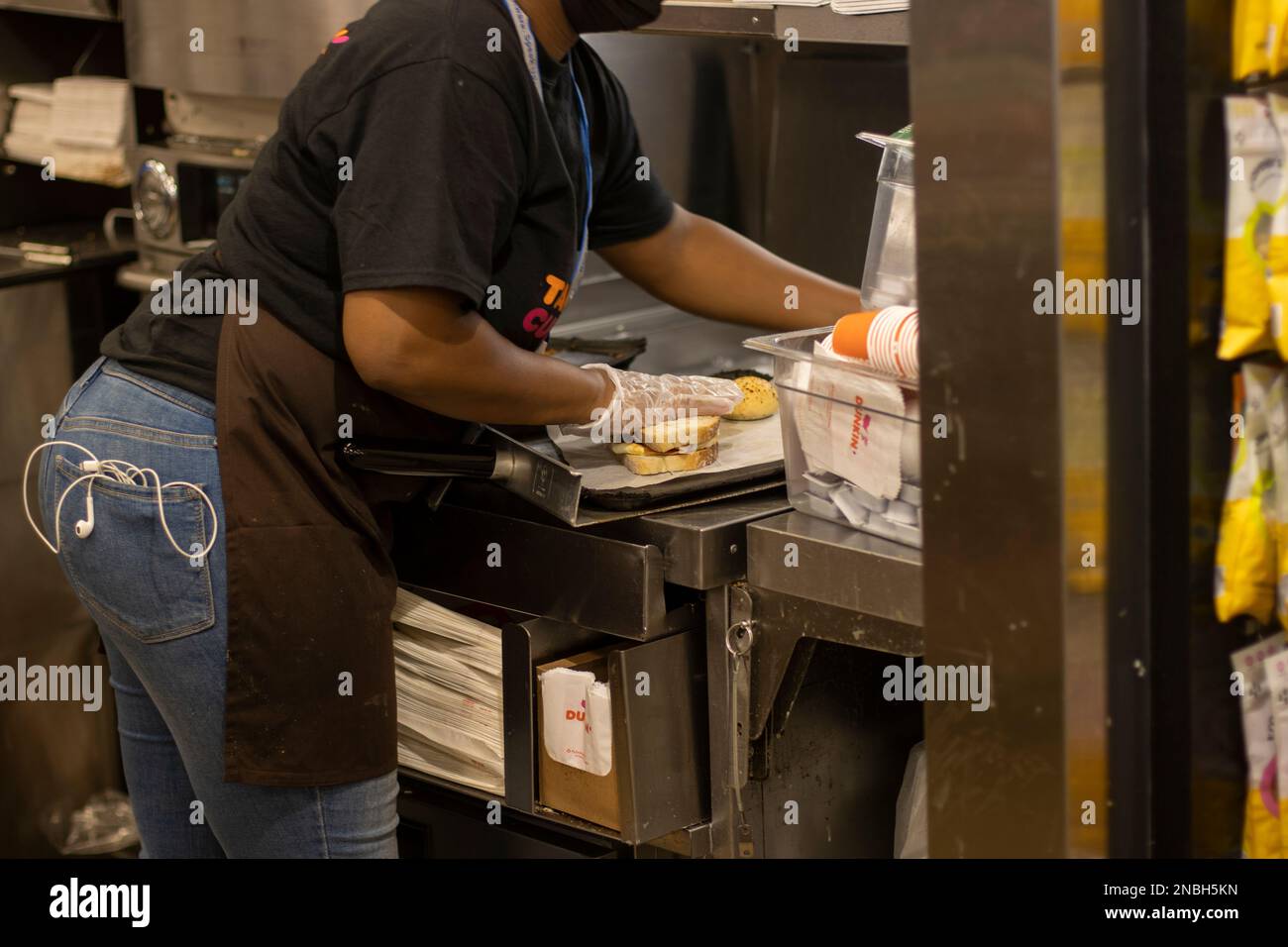 Un travailleur est vu faire un sandwich dans la cuisine d'un magasin Dunkin' Donuts dans le terminal de l'aéroport international John F. Kennedy... Banque D'Images